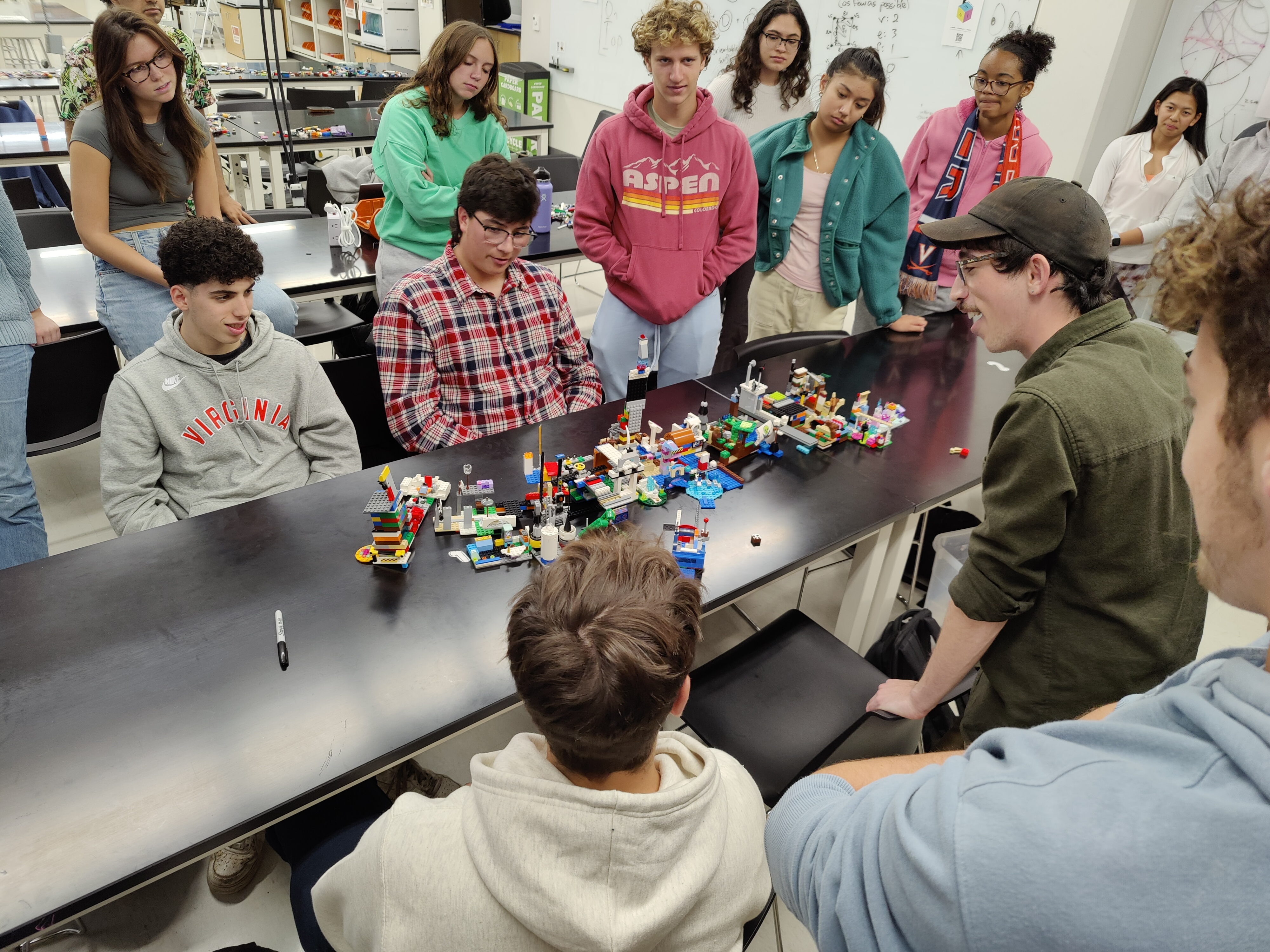 Students gathered around a table looking at a LEGO constructed cityscape