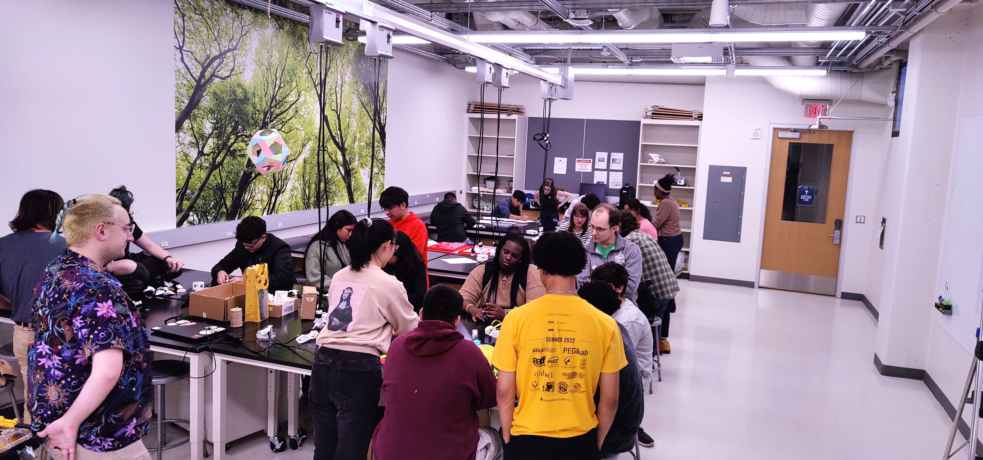 Students in a makerspace with a big poster of trees in the background