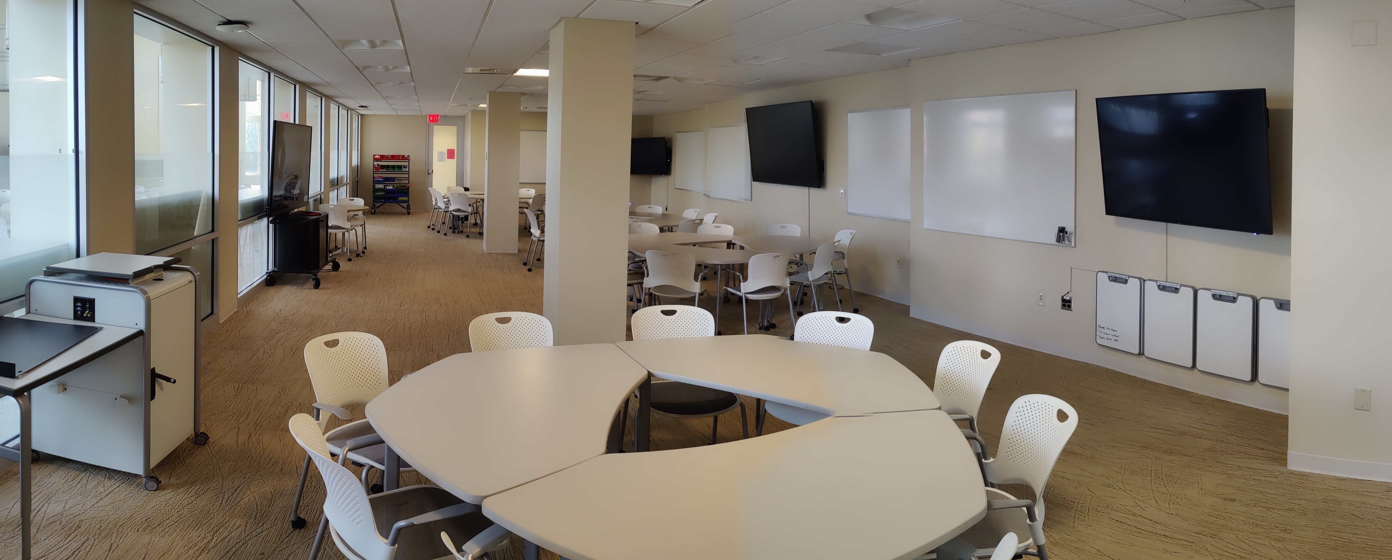 A panorama of a group study space with tables, chairs, whiteboards, and televisions